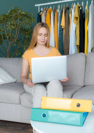 Middle Aged Blond Woman sitting on the sofa and communicates online by Laptop.の写真素材