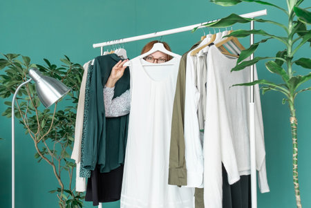 Middle Aged Woman makes shopping and looks at the new dress near shelf with clothes.の写真素材