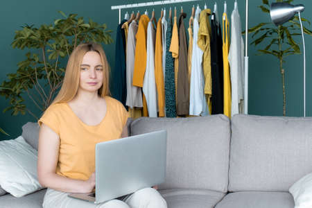 Middle Aged Blond Woman sitting on the sofa and communicates online by Laptop.の写真素材