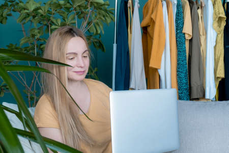 Middle Aged Blond Woman sitting on the sofa and communicates online by Laptop.の写真素材