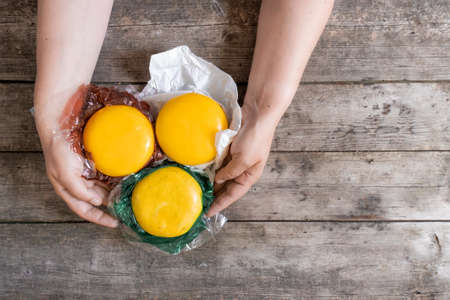 Hands hold whole Holland cheeses and dutch goat cheese from Netherlands on the rustic wooden table, top view.の写真素材