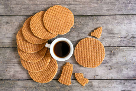 Traditional Holland waffles with caramel and cup of coffee on the wooden background, top view.の写真素材