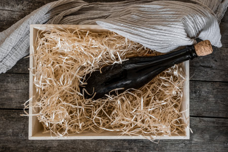 Straw into storage box with bottle of wine on the black wooden background, delivery service.の写真素材