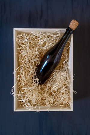 Straw into storage box with bottle of wine on the blue wooden background, delivery service.の写真素材