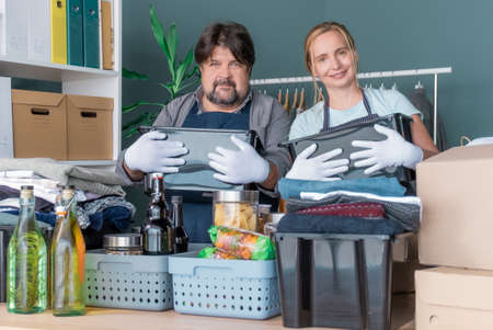 Men and Woman pack in boxes clothes and products for charity and donation.の写真素材