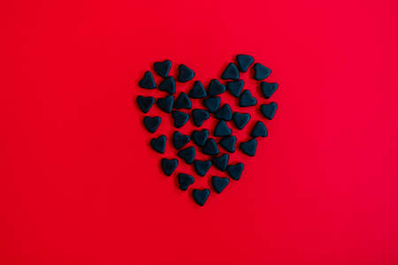 A lot of black candy hearts on the red background. Black Friday or Happy Valentine Day concept.の写真素材