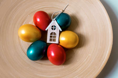 Painted easter eggs red green and gold colors with three toy houses, property sale concept, top viewの写真素材