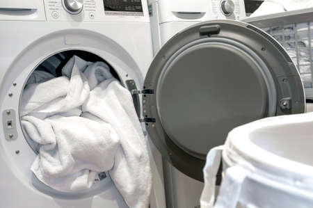 Open door of Dry machine in hotel with white towels in the laundry.の写真素材