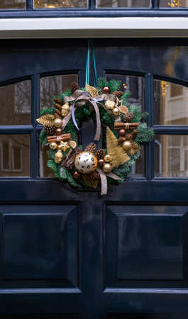 Decoration festive golden wreath hanging on the blue front door of house.の写真素材
