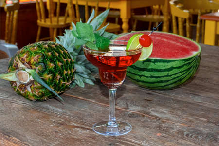 Cocktail Woowoo cherry, lime, mint, cranberry juice and vodka with watermelon and pineapple on the old wooden table.の写真素材