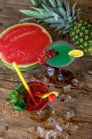 Two Cocktails Woowoo and Blue Curasao with watermelon, pineapple and ice on the old wooden table.の写真素材