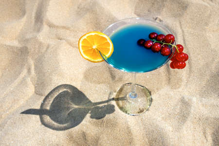 Cocktail Blue Curacao with melon liqueur, pineapple juice, currant and orange on the sand with light and shadow.の写真素材