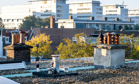Smoke from chimney pipes at the rooftop of ordinary family houses in the Netherlands, sunrise on the roof of the city center.の写真素材