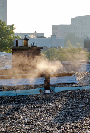 Smoke from chimney pipes at the rooftop of ordinary family houses in the Netherlands, sunrise on the roof of the city center.の写真素材