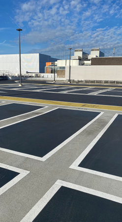 Modern urban parking in a big city with yellow markings and white houses and blue sky in sunny dayの写真素材