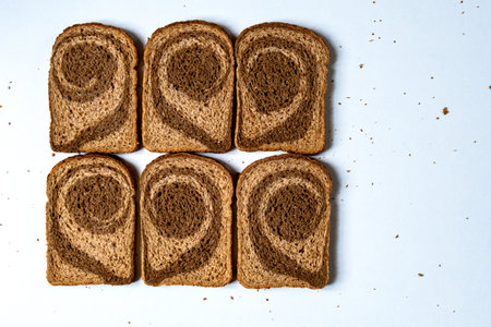 Sliced pieces of dark and light bread dough of coarse grinding in the form of a twisted spiral on a white backgroundの写真素材