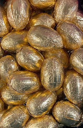 The background of Easter chocolate eggs wrapped in gold foil is a typical sales of sweets for children in Europe, top view.の写真素材