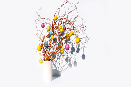 Thin spring branches with yellow and pink eggs on a white background as a symbol of the Easter holiday in Europe, Netherlandsの写真素材