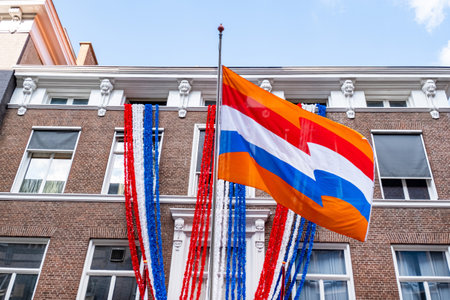 Flag of the Netherlands on the blue sky background and old city center with old Hollands building.の写真素材