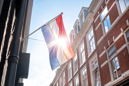 Flag of the Netherlands on the blue sky background and old city center with old Hollands building.の写真素材