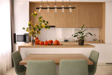 Bright modern interior, with white kitchen and pumpkins on a wooden table.の写真素材