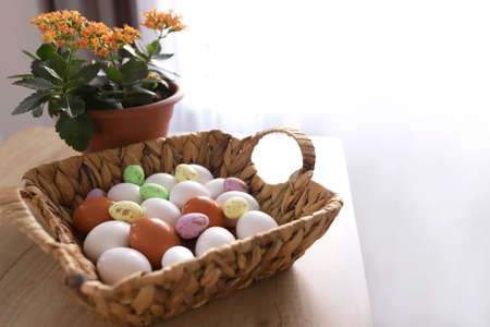 chicken eggs lie with a straw basket on wooden background.. Top view. Free space. Easter eggs. High...