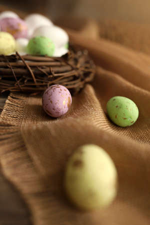 Colored chicken and quail eggs in a nest on a wooden background. Top view. Free space. Easter eggs....