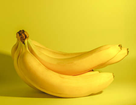 A bunch of fresh ripe bananas lies on a yellow background.の写真素材
