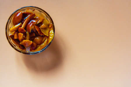 Pickled forest mushrooms in a glass saw on an orange background.の写真素材