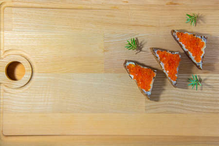 Minimalist sandwiches with caviar on a wooden background with juniper twigs.の写真素材