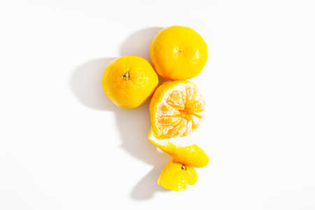 Tangerine half peeled and two whole tangerines lie on a white background. Isolate. Lifestyle....