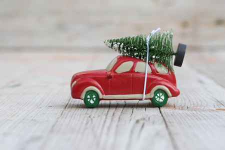 Miniature red car with fir tree on wooden background. Shallow DOFの写真素材
