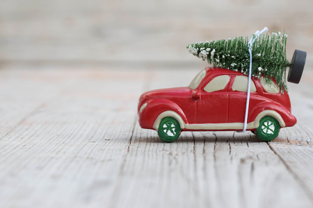 Miniature red car with fir tree on wooden background. Shallow DOFの写真素材