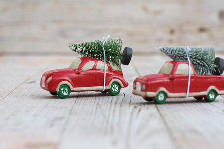 Miniature red car with fir tree on wooden background. Shallow DOFの写真素材