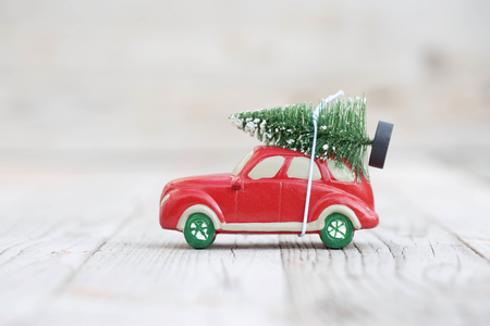 Miniature red car with fir tree on wooden background. Shallow DOFの写真素材