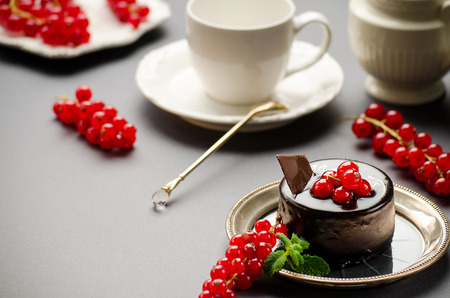 Chocolate cake with a red currant on a dish, cup and milkmanの写真素材