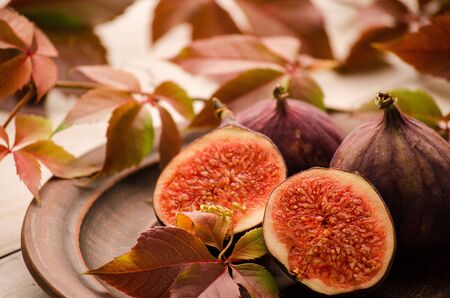 The figs and cut a whole in a clay bowl and vine leavesの写真素材
