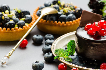 chocolate cake with red currants and two cakes with blueberries on gray backgroundの写真素材
