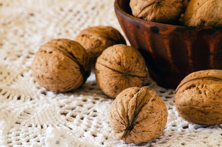 Walnuts in a clay bowl on a table covered with a knitted clothの写真素材