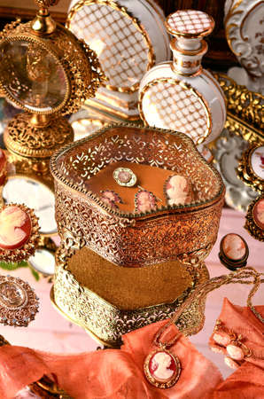 Boudoir table close-up, brooches, jewelry boxes, vintage bottles, white and gold, selective focus.の写真素材