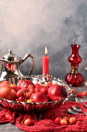 Beautiful still life in red tones, fruits, antique silver, burning candle, selective focus, place for text, Valentine's Day, postcardの写真素材