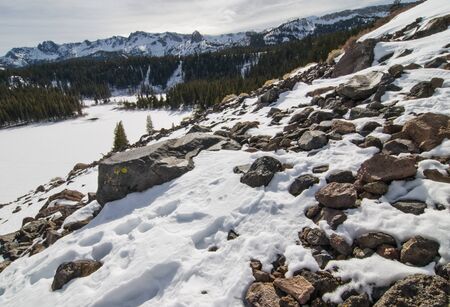Frozen mountainside in Mammoth Lakes, CA overlooking frozen lake with Mammoth Rock in the distance
