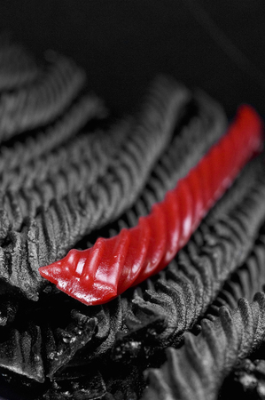 Single red licorice against black licorice candyの写真素材