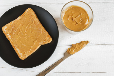 Toast with homemade peanut butter on a black plate. Top view.