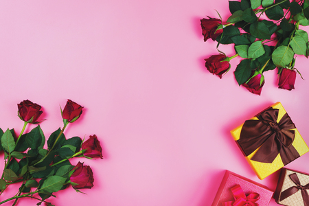 Romantic flat lay with red roses and gift boxes on pink background. Holiday concept, copyspaceの写真素材