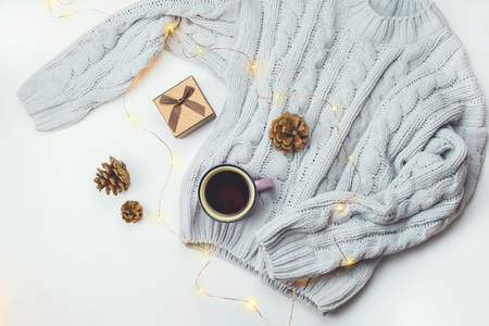 Beautiful flatlay with cozy sweater, Christmas lights and fashion accessories. Concept of cozy winter time. White background.の写真素材