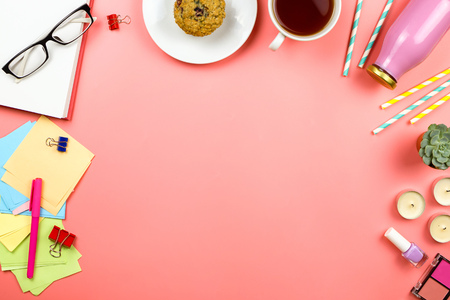 Beautiful flatlay with notebook, glasses, colorful note papers, cup of tea, bottle with juice or smoothie and other accessories. Workplace concept. Pink background, copyspace.の写真素材