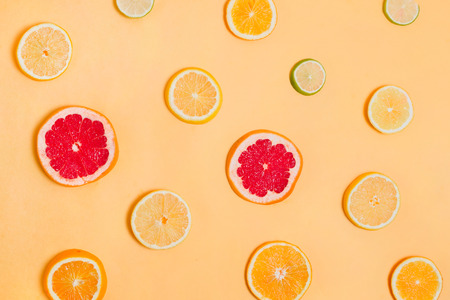 Pieces of various citrus fruits on orange background, concept of healthy eating, flatlayの写真素材
