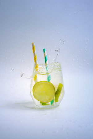 Cup with splashing lime water and paper straws, selective focus.の写真素材