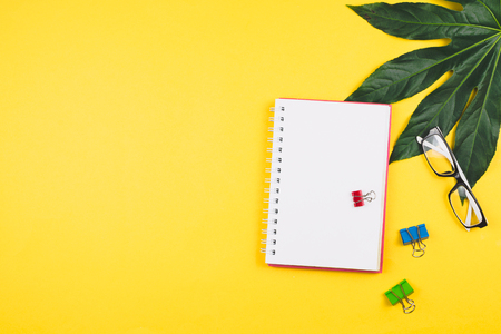 Business flatlay with tropical leaves and business accessories: planner, glasses, clips, etc. Copyspaceの写真素材